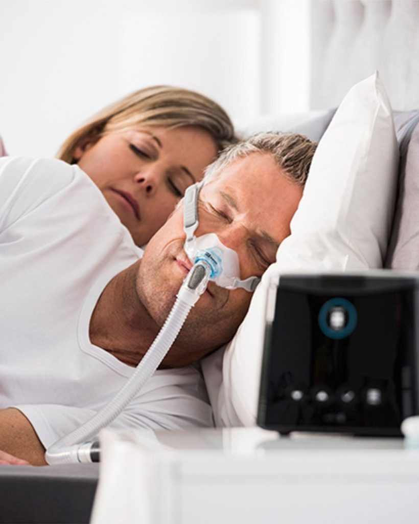 Homem utilizando máscara CPAP para dormir.